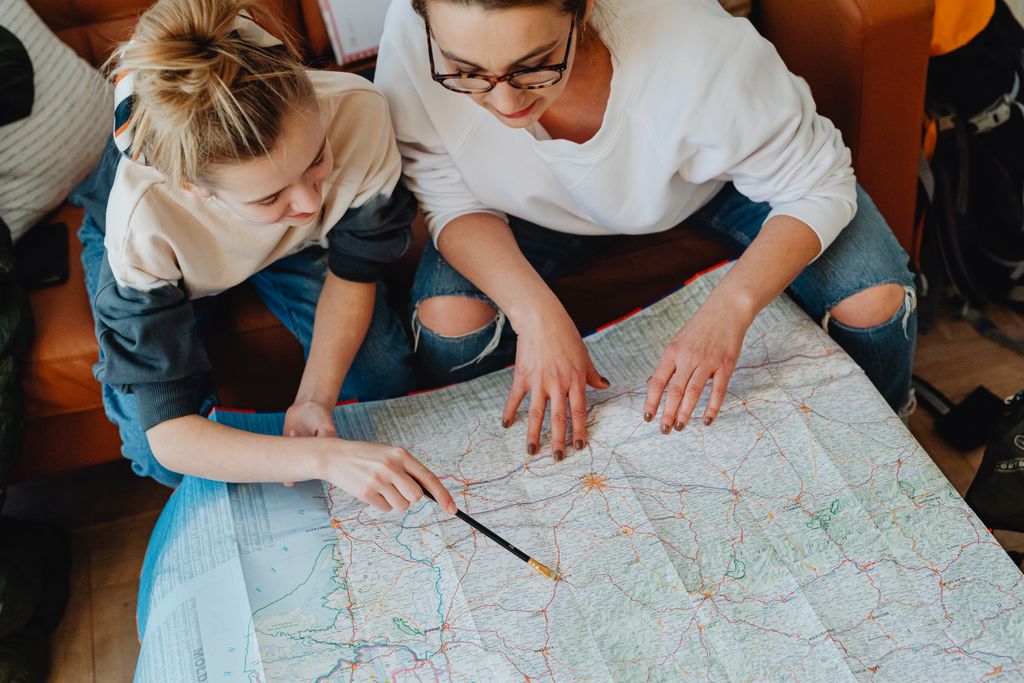 A mother and daughter plan their journey using a map, symbolizing adventure and bonding.